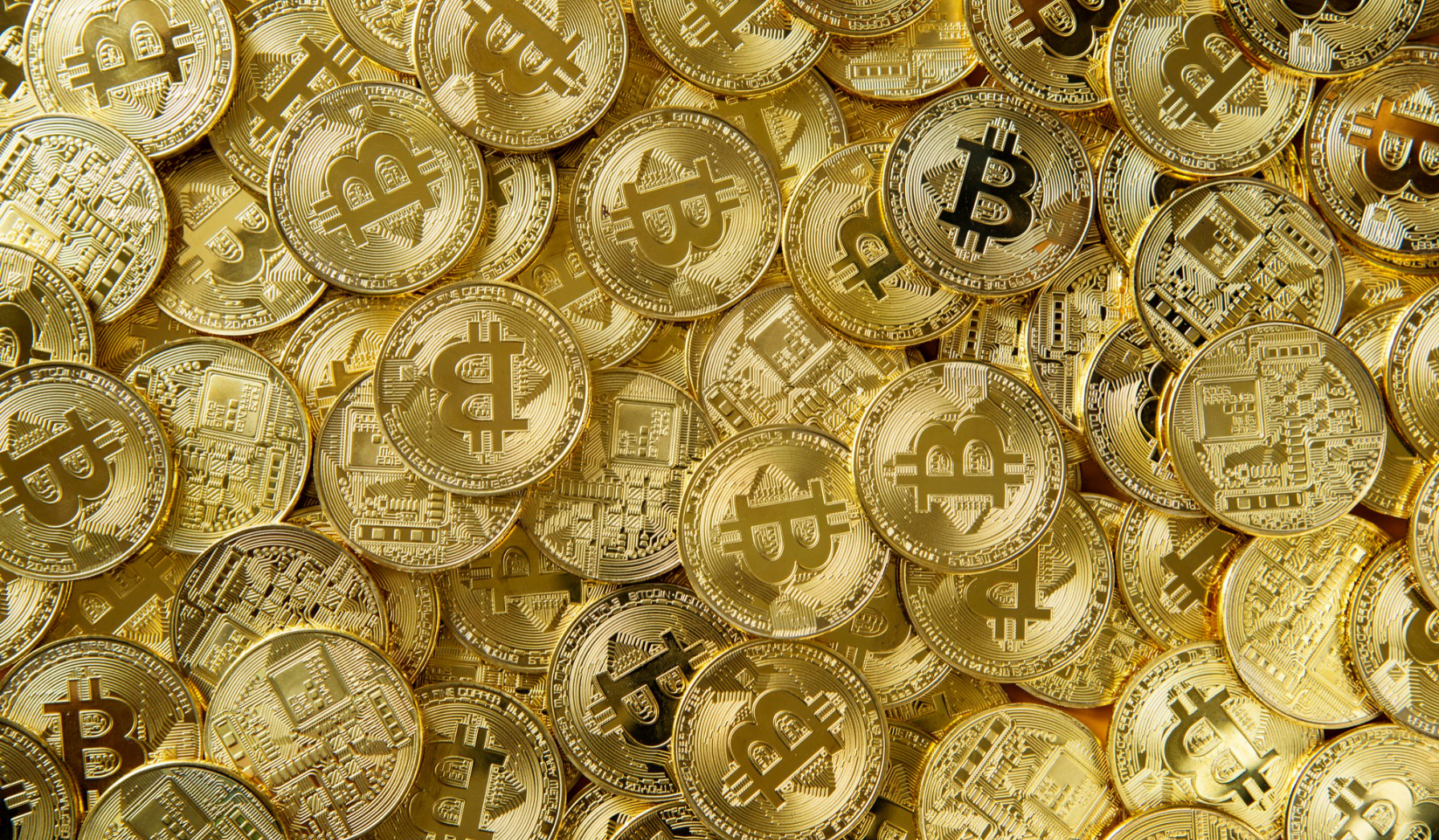 Stos złotych monet z logiem Bitcoina